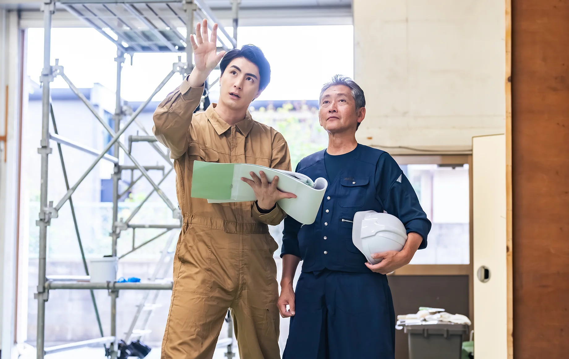 施工現場で図面を確認する建築スタッフ